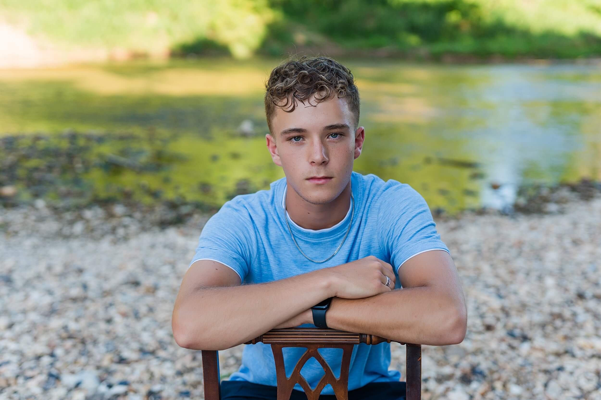 Example Shoot Title Tag A teenage boy sits backwards on a chair leaning on the back in a blue shirt for an Arkansas senior photographer