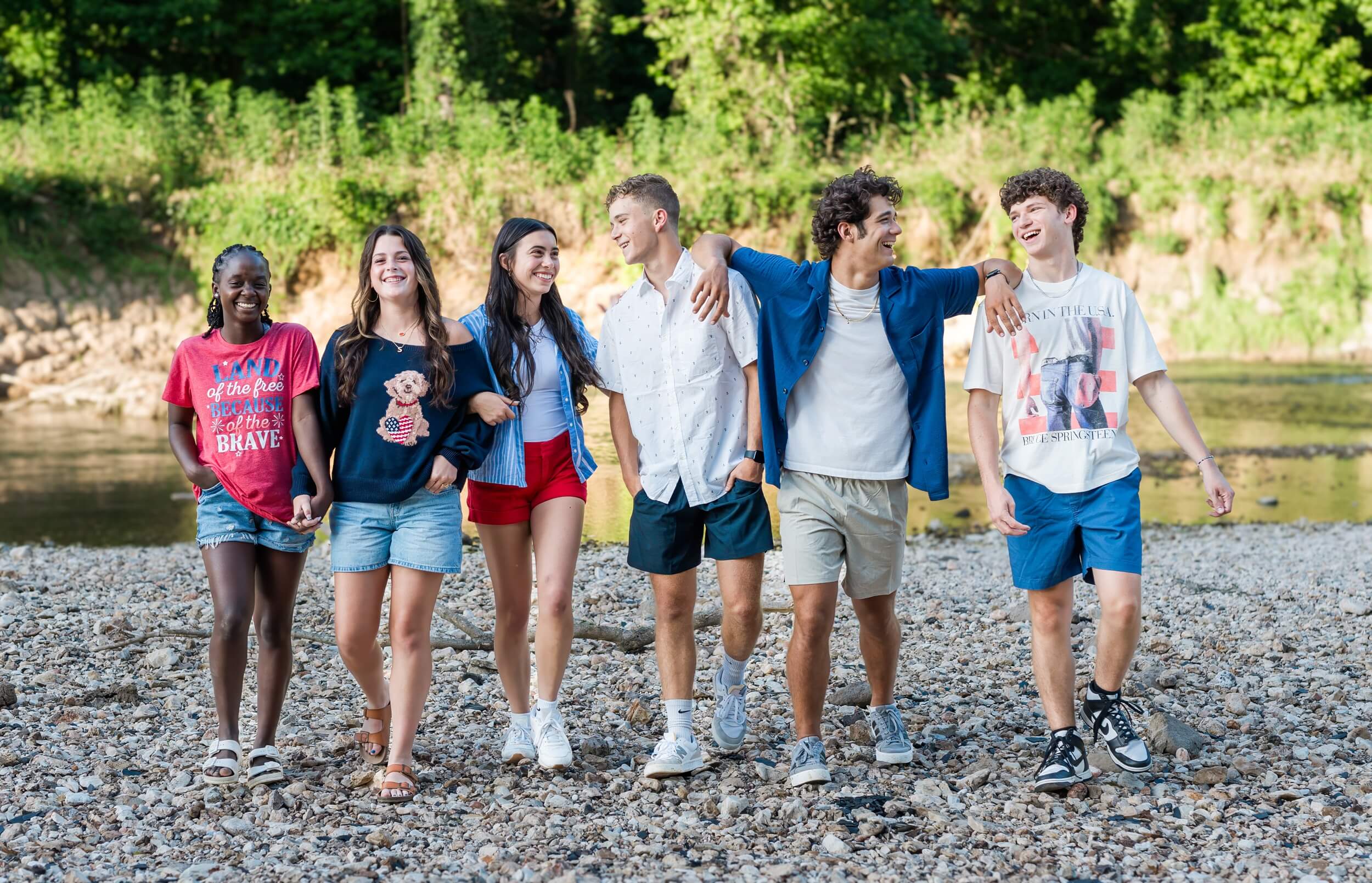 Example Shoot Title Tag A group of high school seniors walk on a riverbed laughing at each other while holding hands and leaning on each other