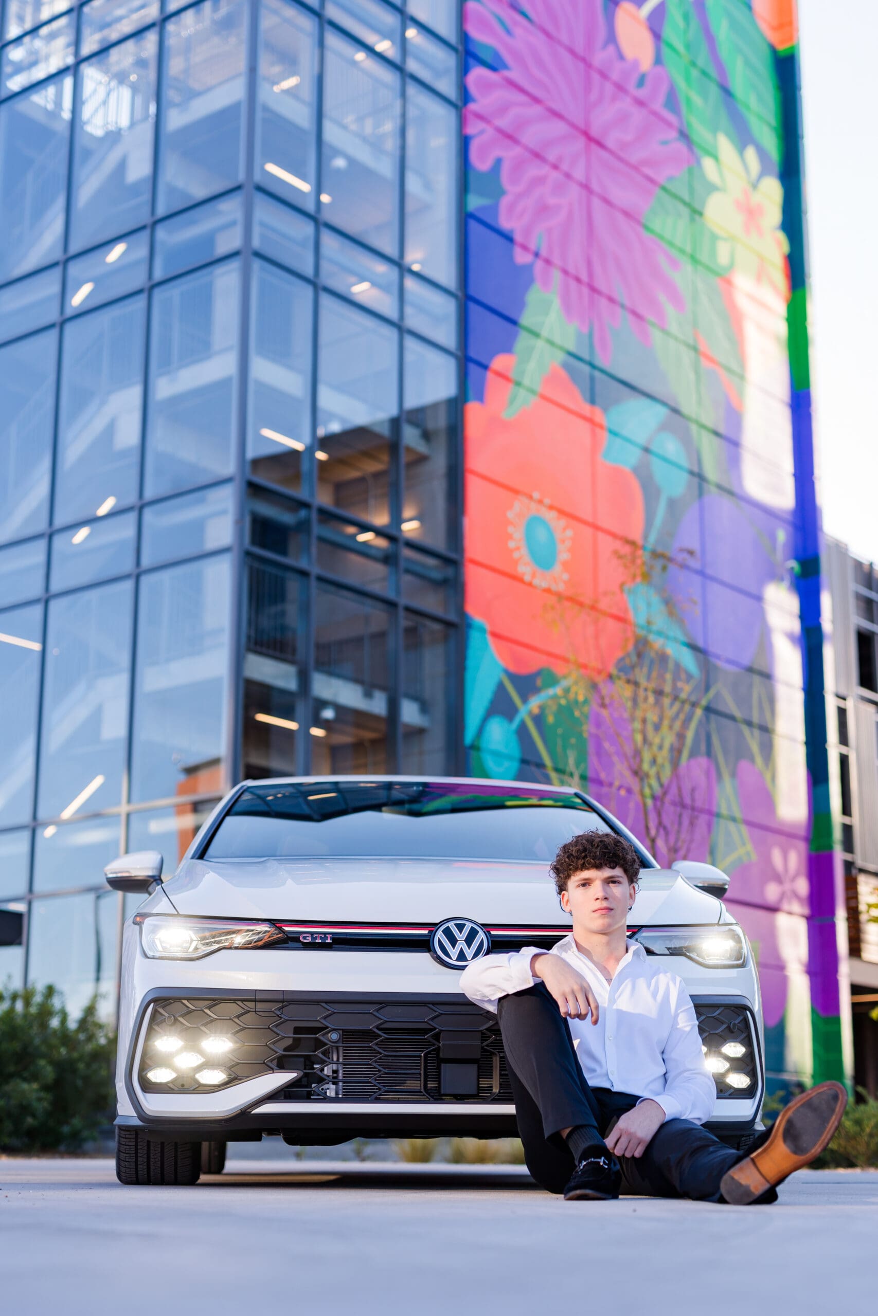 Arkansas Senior boy posing with car in front of flower mural.