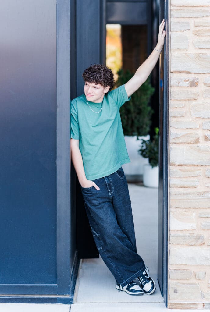 Arkansas Senior guy leaning against black wall in downtown Bentonville.