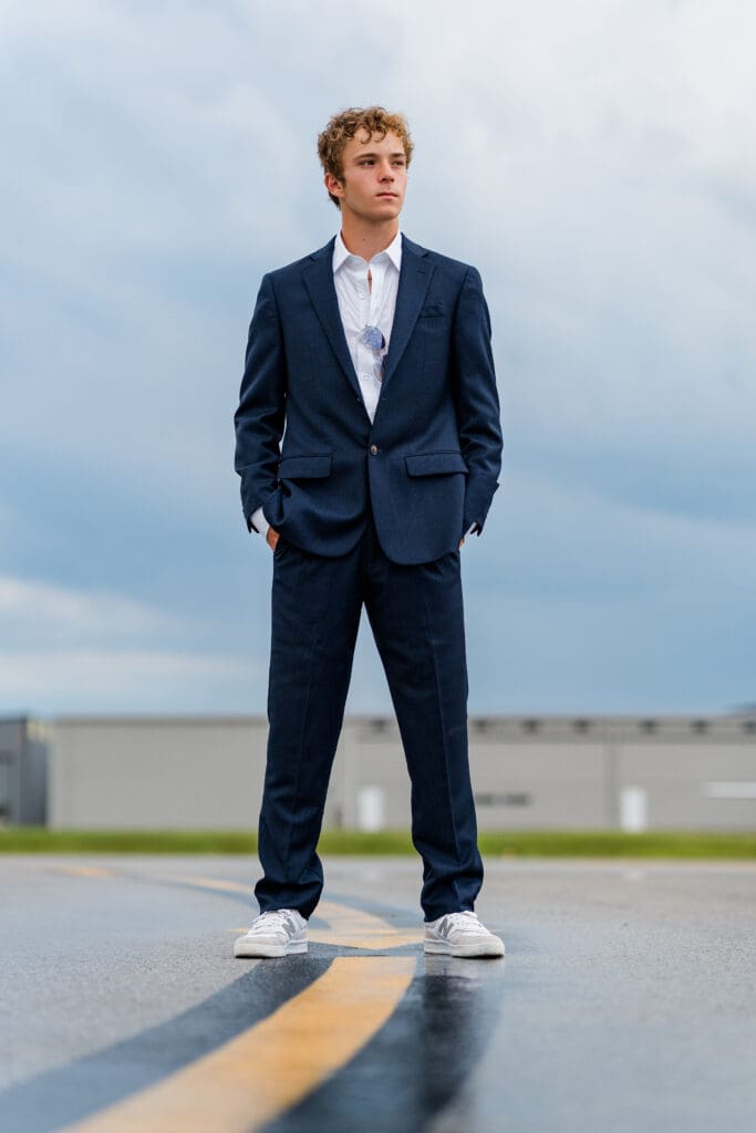 Arkansas senior in suit posing at airport. 