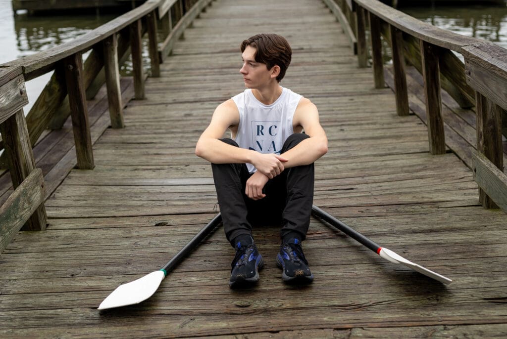 Arkansas senior from Hass Hall academy sitting at Lake Fayetteville with rowing oars. 