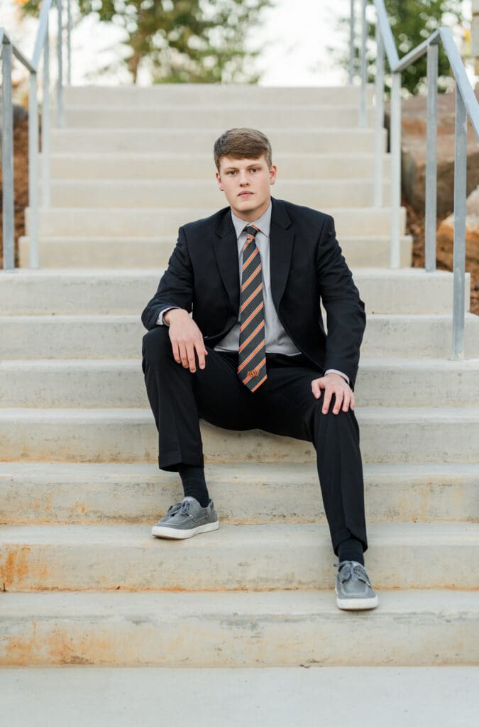 Arkansas senior in suit sitting on steps.