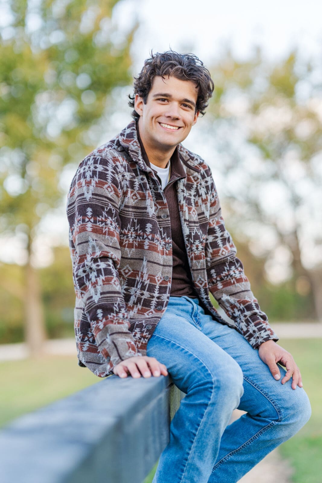 Arkansas senior boy sitting on fence in rural setting. 